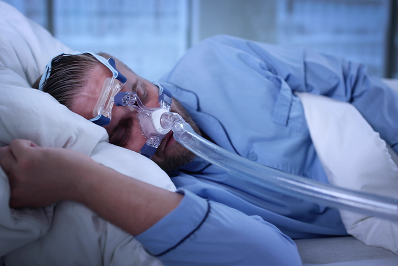 man wearing a CPAP machine in bed