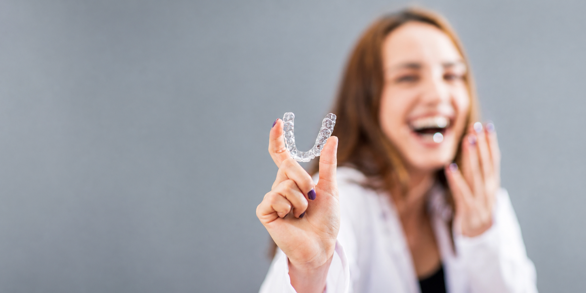 a girl smiling and holding an invisalign